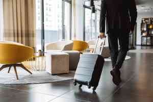 © Drobot Dean - stock.adobe.com Mann zieht Koffer in Hotellobby